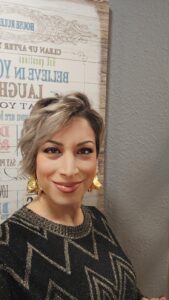 Kobani Festival woman with short blonde hair and gold earrings, celebrating culture and community.