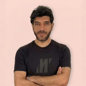 Young man with dark hair and beard posing confidently at Kobani Festival, celebrating Kurdish culture and heritage.