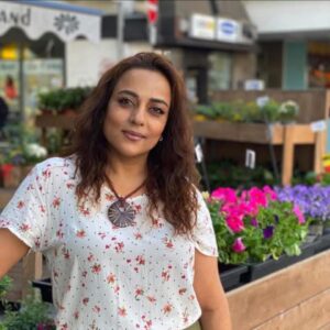 Vibrant woman at Kobani Festival with colorful flowers in the background.